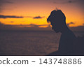 夕陽西下，一位年輕男子側臉祈禱。 143748886