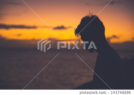 夕陽西下,一位年輕男子側臉祈禱。 夕陽西下,一位年輕男子側臉祈禱。 143748886