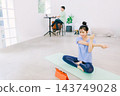 A wife doing yoga in the living room while her husband works in the back. A wife doing yoga in the living room while her husband works in the back. 143749028