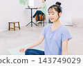 A wife doing yoga in the living room while her husband works in the back. A wife doing yoga in the living room while her husband works in the back. 143749029