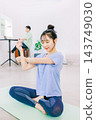 A wife doing yoga in the living room while her husband works in the back. A wife doing yoga in the living room while her husband works in the back. 143749030