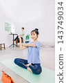 A wife doing yoga in the living room while her husband works in the back. A wife doing yoga in the living room while her husband works in the back. 143749034