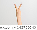 一隻塗著銀色閃光指甲油的日本女性的手，在灰色背景下比出和平手勢。 143750543