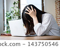 一位日本女性在辦公室裡看著筆記型電腦，陷入沉思。 143750546