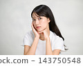 身穿白色T恤的日本女子，雙手托著臉頰和下巴，神情嚴肅地凝視著前方。 143750548