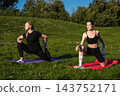 Two women practicing yoga on colorful mats in a sunny outdoor setting 143752171