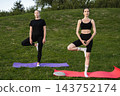 Practicing yoga poses on a sunny afternoon in a park setting 143752174