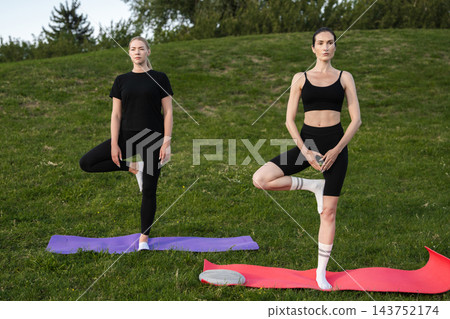 Practicing yoga poses on a sunny afternoon in a park setting 143752174