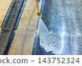 Pressure washer sprays water over paving car carpet cleaning of surface outdoors. 143752324