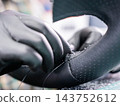A seamstress in a workshop makes a new leather cover for a car steering wheel. 143752612
