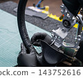 A seamstress in a workshop makes a new leather cover for a car steering wheel. 143752616