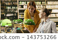 Student tutoring, laptop and classmates bring woman in yellow beside peer reviewing work at a library desk. Mentorship, academic support and collaboration encourage shared learning and progress. 143753266
