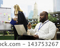 Businessman, laptop and strategy as seated professional gestures with pen while colleagues work beside whiteboard. Planning, productivity and collaboration support teamwork in outdoor urban workspace. 143753267