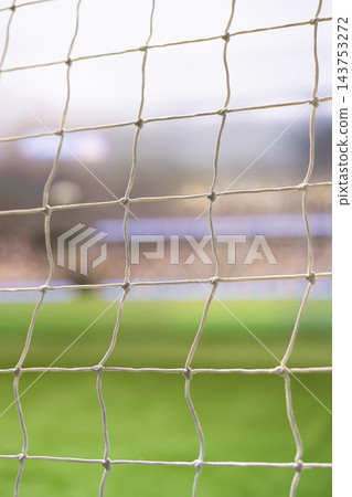 Football goal, net and copy space frame close detail of rope grid against softly blurred green field and crowded stands. Soccer, sports advertising and competition offer neutral match backdrop. Football goal, net and copy space frame close detail of rope grid against softly blurred green field and crowded stands. Soccer, sports advertising and competition offer neutral match backdrop. 143753272