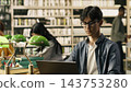 Laptop, coursework and student as young man with glasses works independently at a library computer. Concentration, academic research and productivity support digital study beside books and lamps. 143753280