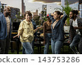 Friends dancing together at urban rooftop barbecue and cookout, capturing energetic group party centered on social connection, recreation, leisure and shared fun. 143753286