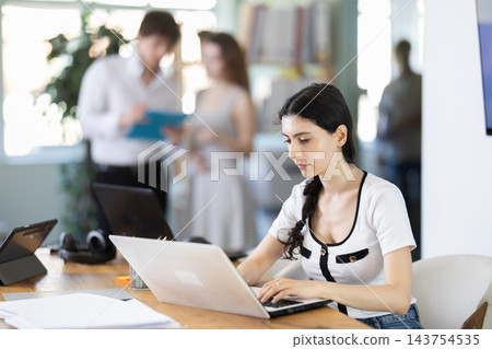 Girl sitting at desk is working on laptop computer. Girl sitting at desk is working on laptop computer. 143754535