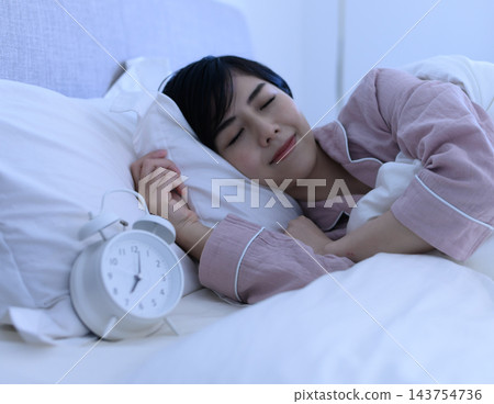 一個女人睡著時身邊放著鬧鐘 一個女人睡著時身邊放著鬧鐘 143754736