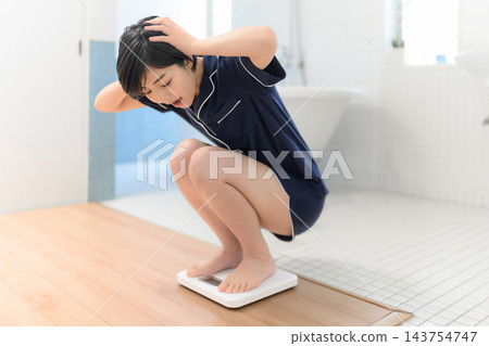 一位女士對體重計上的讀數感到不安。 143754747