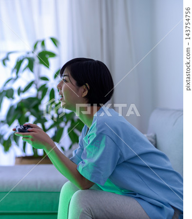 A woman holding a game controller at home A woman holding a game controller at home 143754756