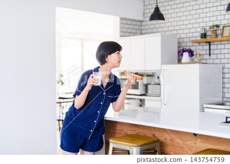 一位女士早餐在吃麵包和牛奶。 一位女士早餐在吃麵包和牛奶。 143754759