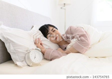 一個女人睡著時身邊放著鬧鐘 一個女人睡著時身邊放著鬧鐘 143754765