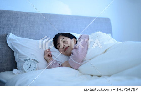 一個女人把臉埋進枕頭裡，鬧鐘響了。 143754787