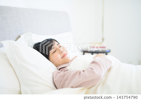 一位女子睡在白色床單上，神情安詳。 143754790