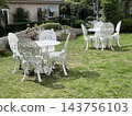 A white table and chairs placed in a lush garden. 143756103