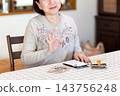 Middle-aged and senior women make a circle pose while calculating money on a calculator. 143756248
