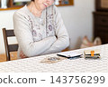 Middle-aged and senior women worrying while calculating money on a calculator. 143756299