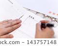A middle-aged/senior woman's hands as she writes her resume in her living room at home. 143757148