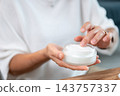 Close up of a woman's hands of senior woman touching moisturizer cream in jar. 143757337