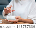 Close up of an elderly woman testing facial moisturizer cream texture on finger. 143757339