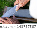 The hands of an old man sharpening a knife 143757567