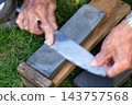 The hands of an old man sharpening a knife 143757568