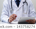 A close-up of a doctor using a digital tablet PC for medical examinations. He is wearing a white coat and has a stethoscope around his neck. 143758274
