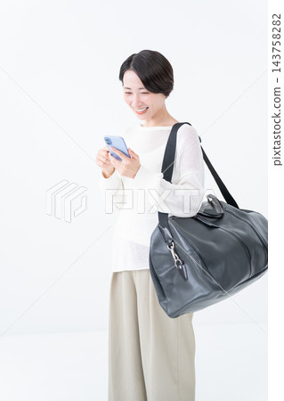 一位女士拎著大包和智慧型手機出門。 143758282