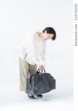 一名女子提著一個沉重的包包 143758283
