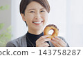 一位女士正在吃甜甜圈。 143758287