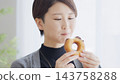 一位女士正在吃甜甜圈。 143758288