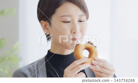 一位女士正在吃甜甜圈。 143758288