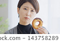 一位正在節食的女士正在猶豫要不要吃一個甜甜圈。 143758289