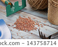 Small seeds scattered beside gardening tools on a wooden work surface 143758714