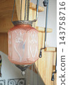 Hanging pink glass ceiling light with metal chains in a wooden interior 143758716