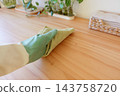 Hand wiping a wooden kitchen counter with a cloth during daytime 143758720