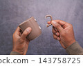 Hands hold a broken brown mug and its detached handle 143758725
