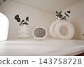 Digital thermometer and plant decor arranged on an indoor shelf 143758728