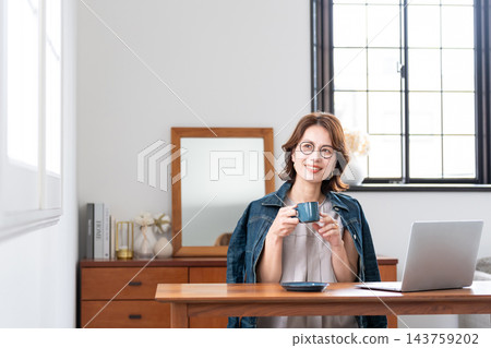 在客廳裡使用電腦的中年女人 在客廳裡使用電腦的中年女人 143759202
