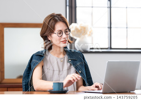 一位中年婦女在客廳使用電腦。 一位中年婦女在客廳使用電腦。 143759205